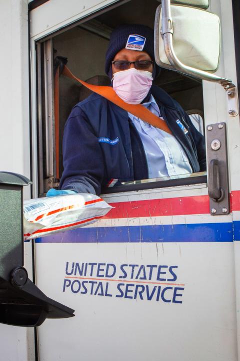 A U.S. Postal Service worker making a delivery from an agency truck.