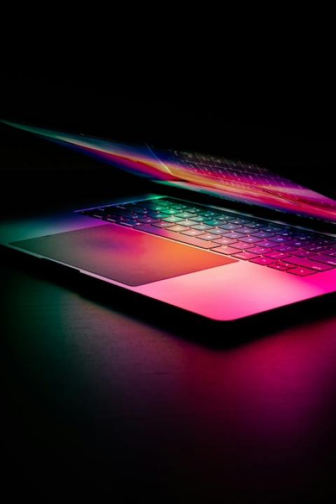 A laptop lit by multicolor light — artificial intelligence