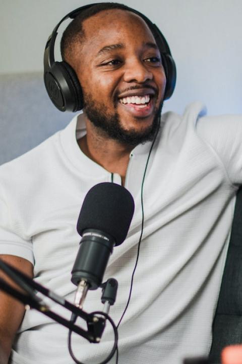 A man with headphones on speaks into a microphone. 