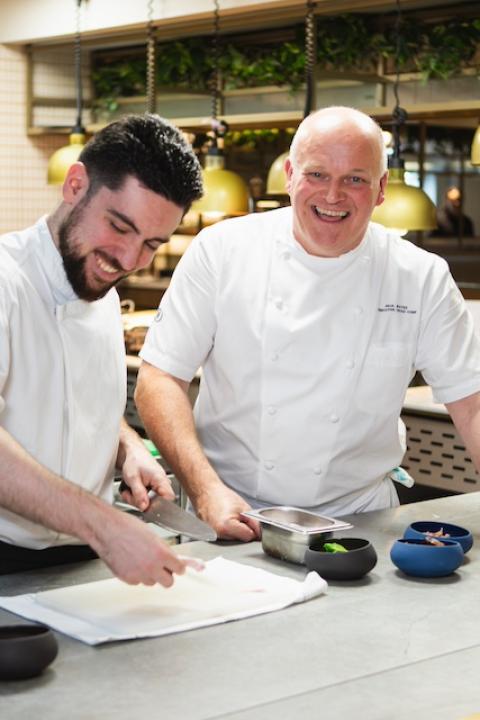 Two Hilton chefs work together to prep ingredients in a hotel kitchen — food waste