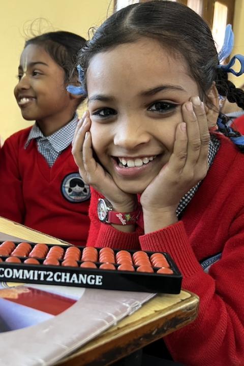 Students smile while sitting in a Commit2Change math class — International Day of the Girl