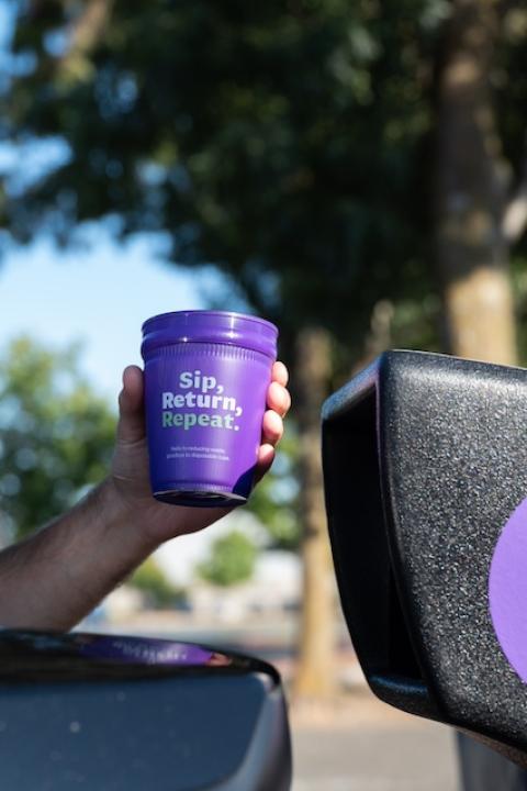 A person uses a drive-up drop off bin to return their purple, reusable cup as a part of the Petaluma Reusable Cup Project.
