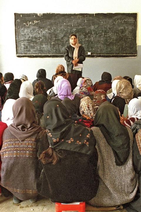 A class of young women sits in a school room in Afghanistan with a teacher at the front.