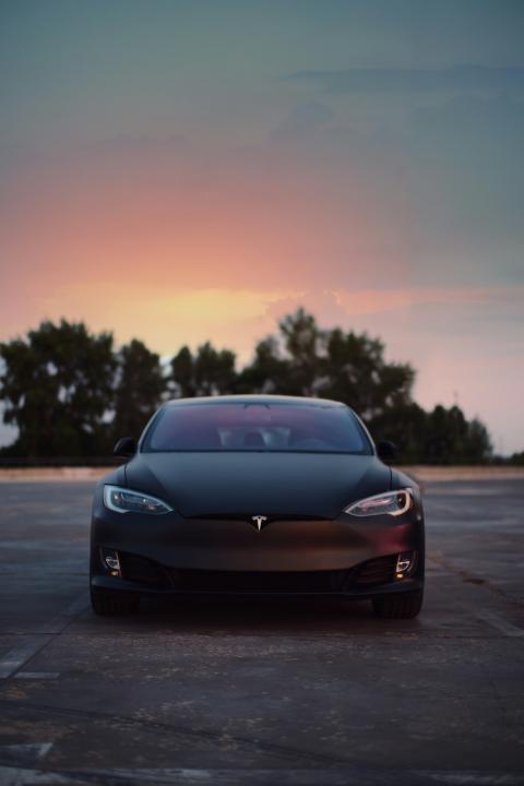 black tesla parked outside at sunset