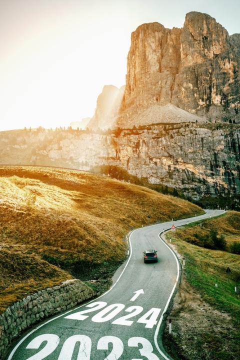 car driving down a road with a direction sign pointing to 2024 - new year