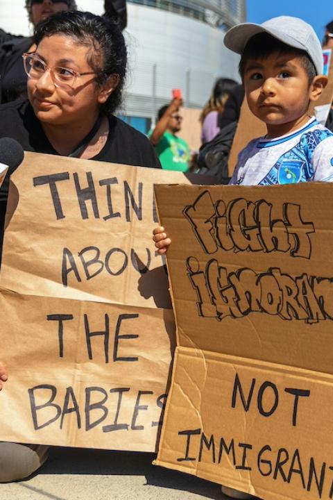 A mother and child hold signs that read, "Think about the babies," and "Fight ignorance not immigrants," at a protest in California.
