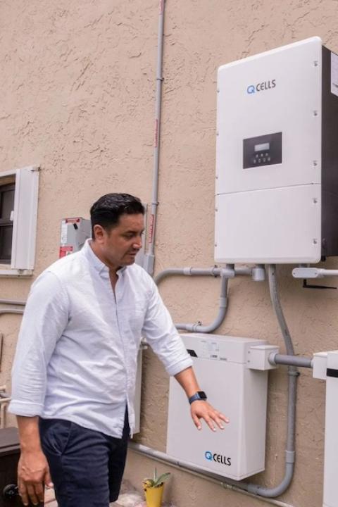 Luis Galarza stands next to part of a solar system on a home. 