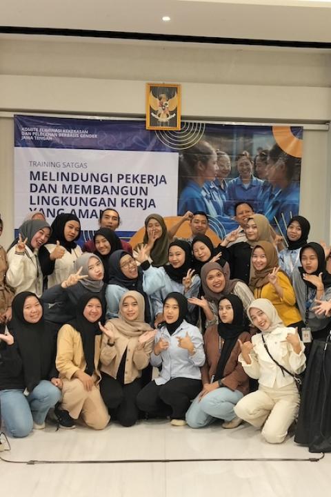 Garment factory workers and union members smile at the camera for a group photo at a training session — gender justice agreement