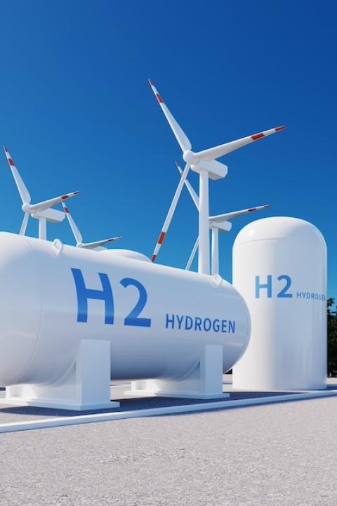 A rendering of a hydrogen storage tank near wind turbines and solar panels — green hydrogen