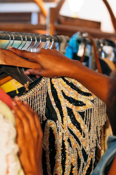 A person looking though a rack of secondhand clothing — tariffs 
