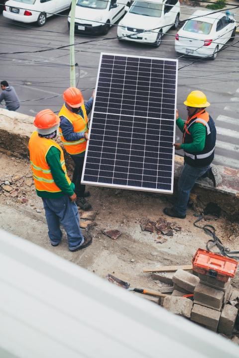 solar installers moving solar panel onto roof