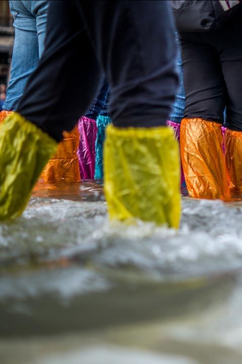 tourists try to stay dry during flooding in venice - disaster risks