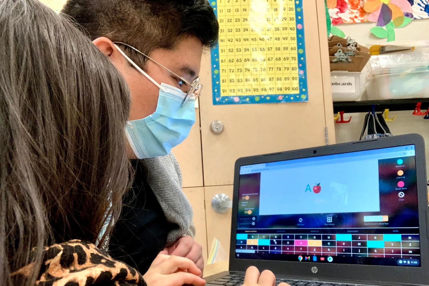 A child working on a computer with a Chapter One tutor. 