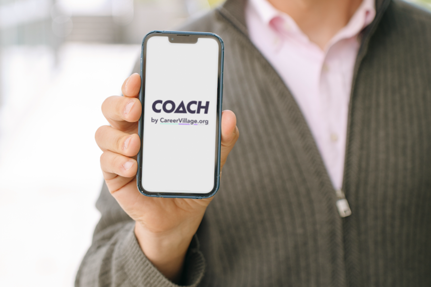 CareerVillage Founder Jared Chung holds a phone showing the welcome page of the organization's AI career coach.