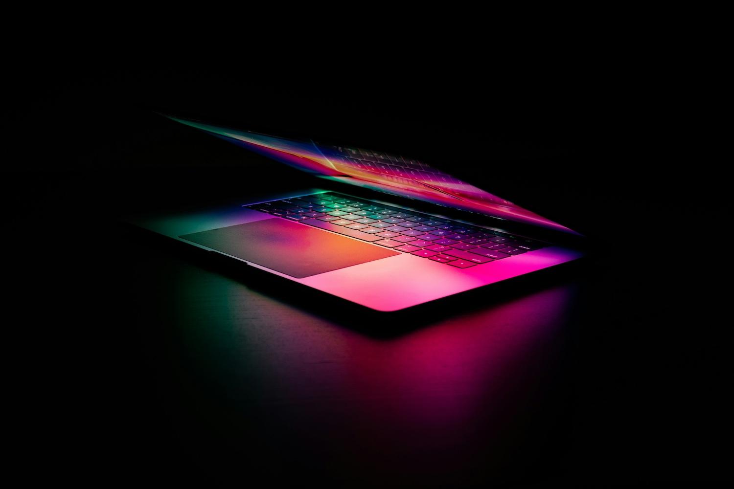 A laptop lit by multicolor light — artificial intelligence