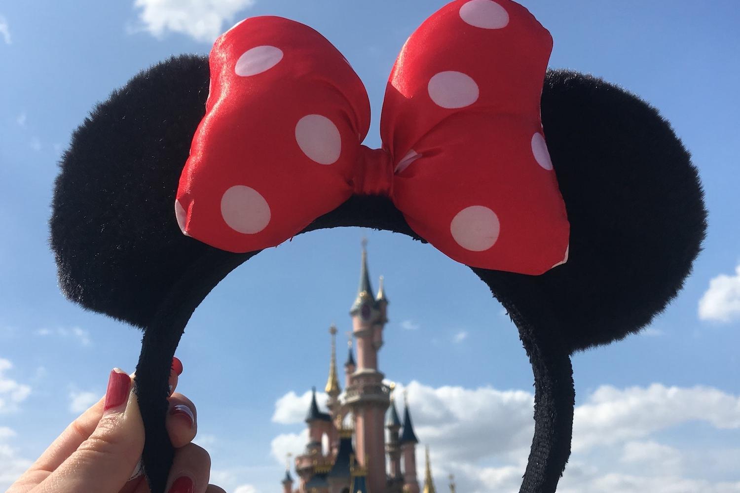 Disney World — woman holds Minnie Mouse headband over magic castle