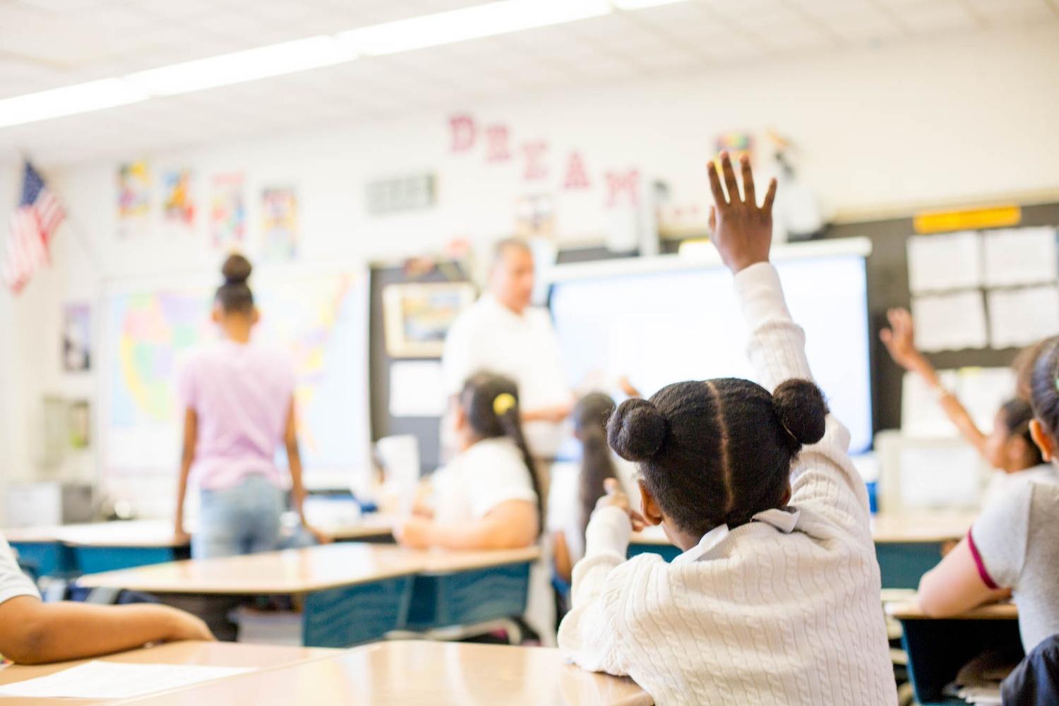 A student raising their hand in a classroom — DonorsChoose