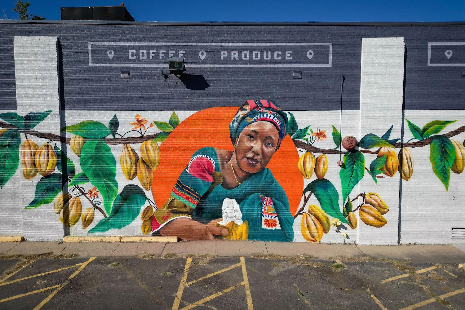 The Denver mural depicting Salamatu Katta in an orange circle surrounded by a cacao tree on the wall of Leevers Locavore in Denver, Colorado — Fairtrade farmers