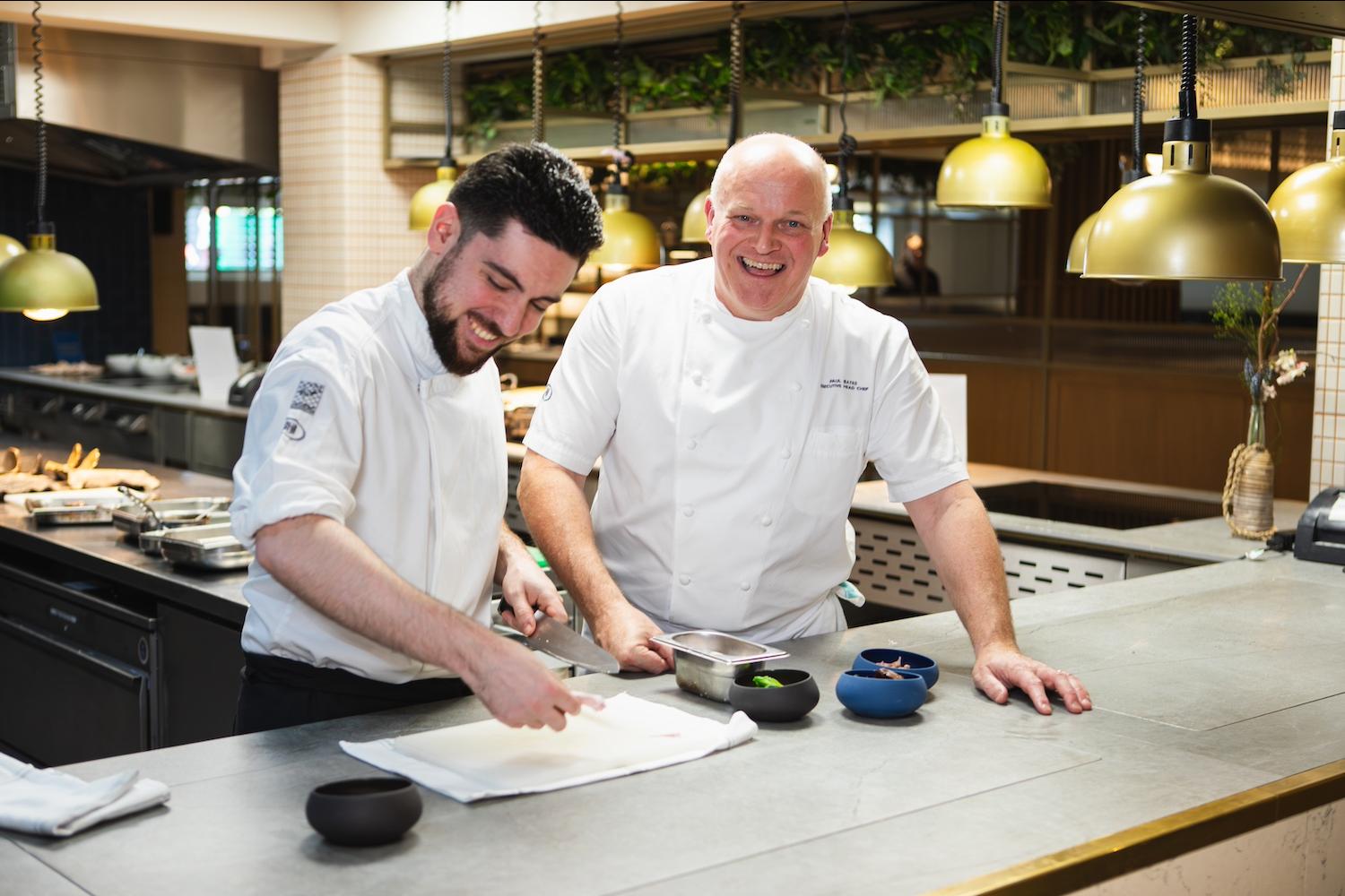Two Hilton chefs work together to prep ingredients in a hotel kitchen — food waste