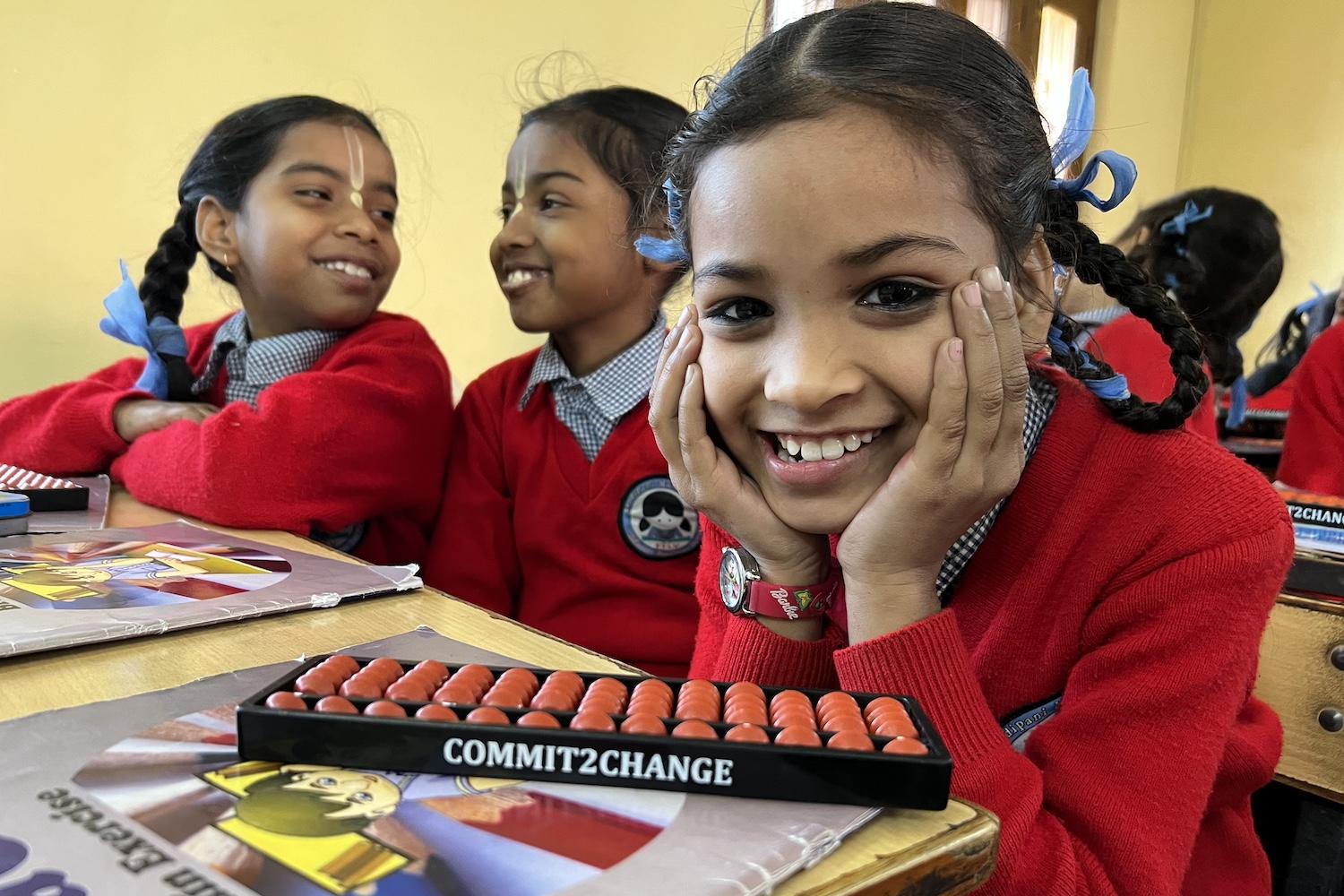 Students smile while sitting in a Commit2Change math class — International Day of the Girl