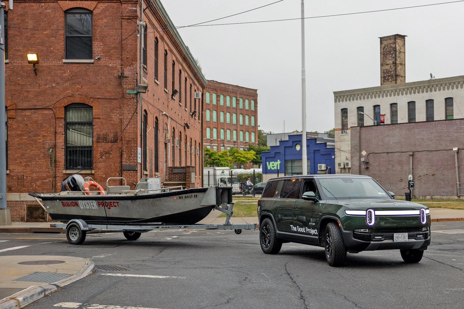 A green Rivian R1 pulling a Billion Oyster Project boat — The Good Project