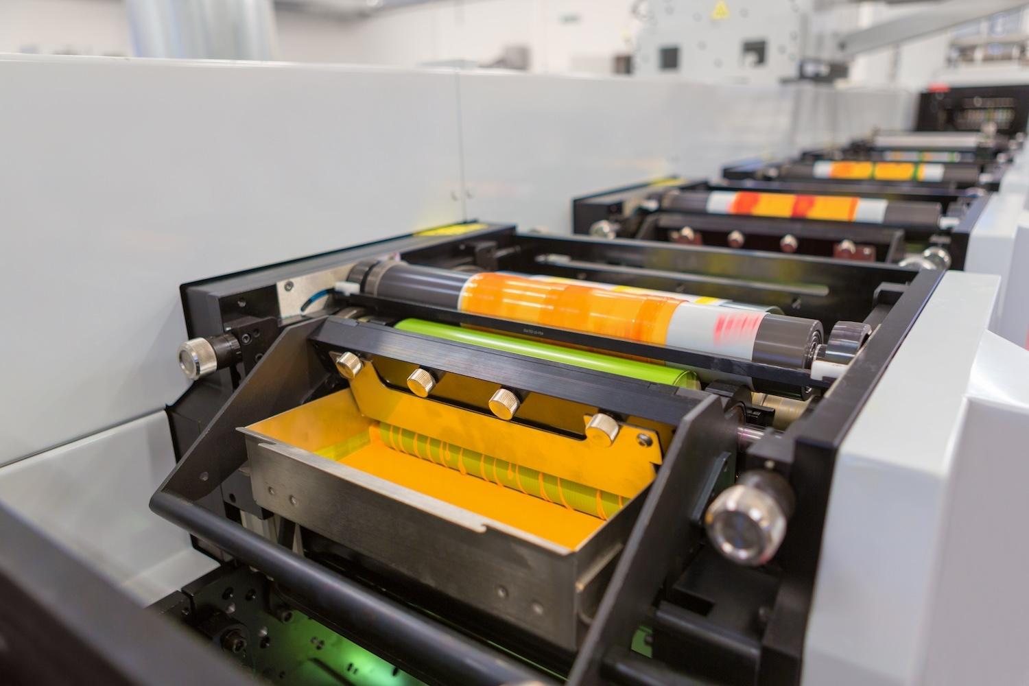 A flexographic printing machine rolling yellow ink onto packaging material — VOC