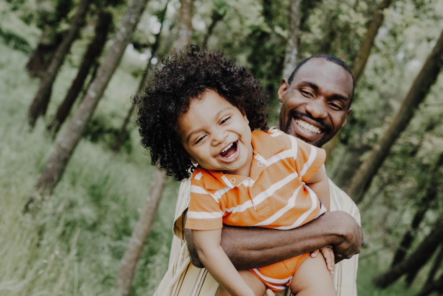 child laughing in fathers arms outdoors