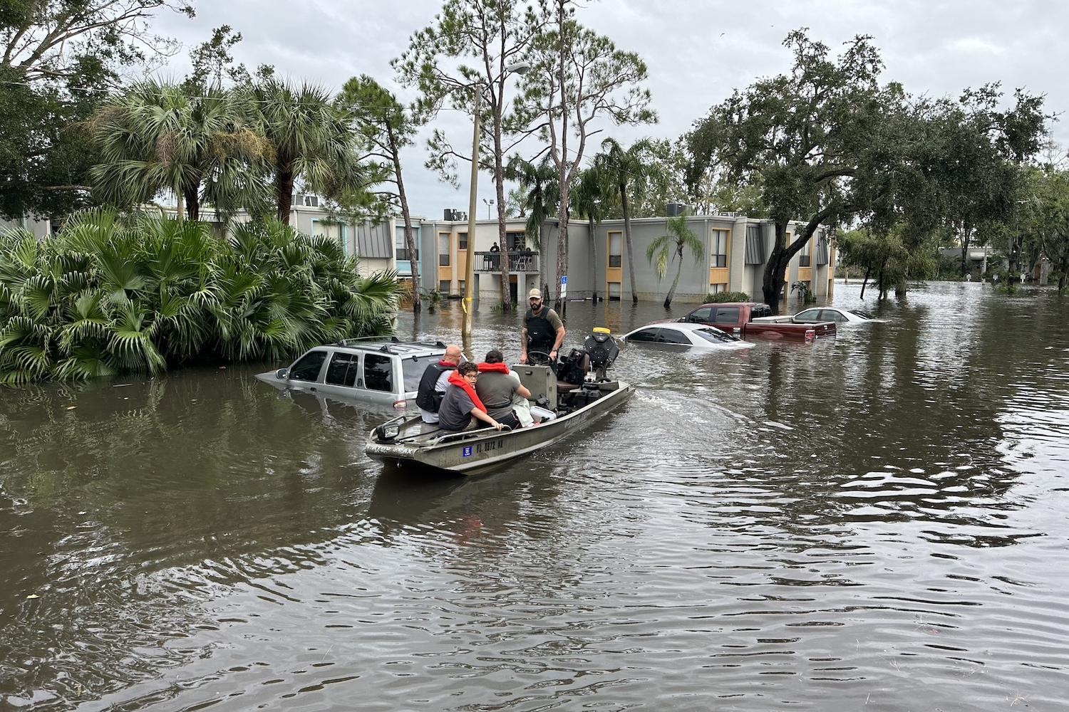 A Florida Fish and Wildlife Conservation Commission officer uses a boat to help people get out of a flooded area — climate resilience