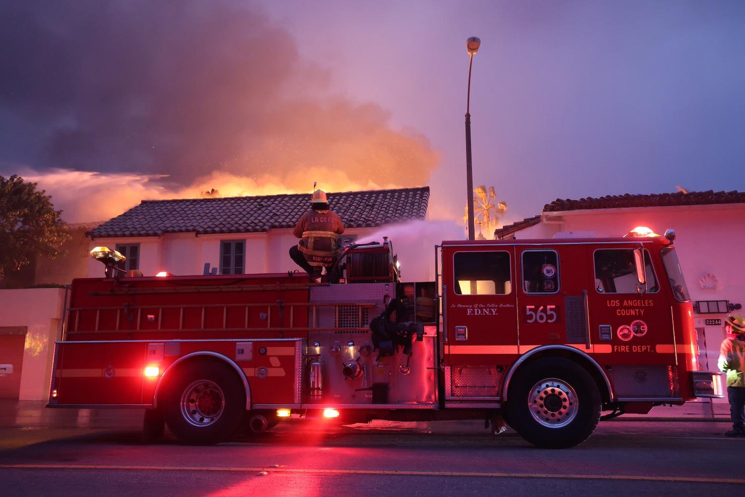 A firefighter sprays water onto a fire from the top of a firetruck — evacuation