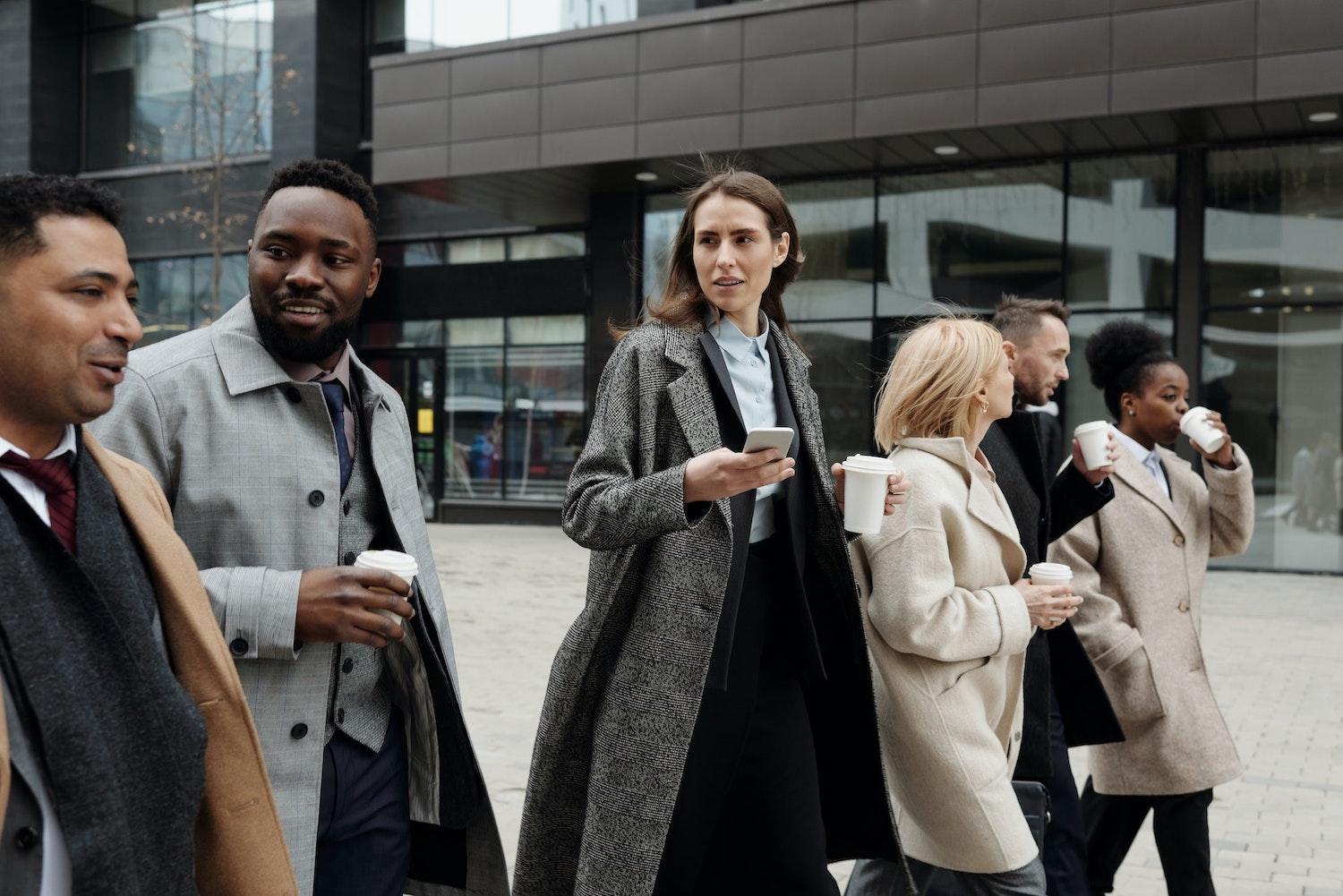 diverse coworkers professionals in business attire walking to work - corporate diversity disclosures are rising