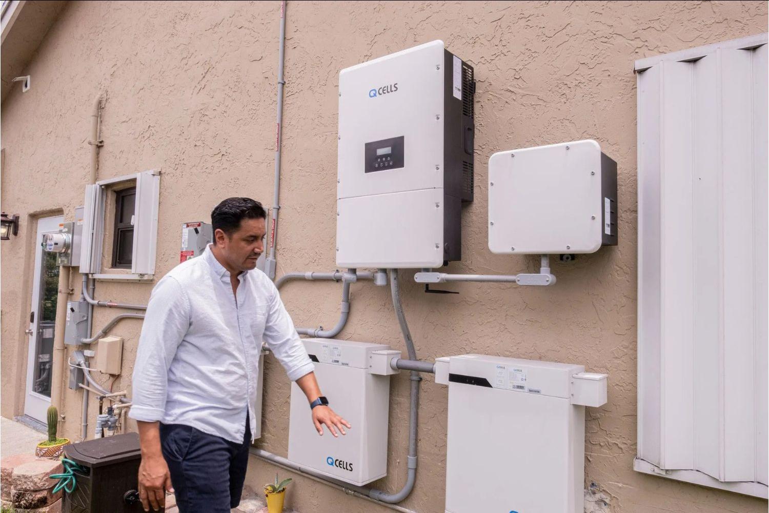 Luis Galarza stands next to part of a solar system on a home. 