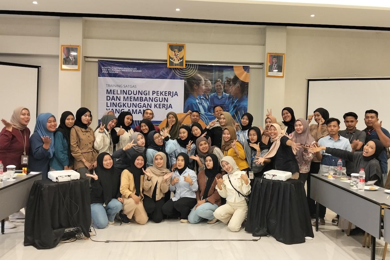 Garment factory workers and union members smile at the camera for a group photo at a training session — gender justice agreement