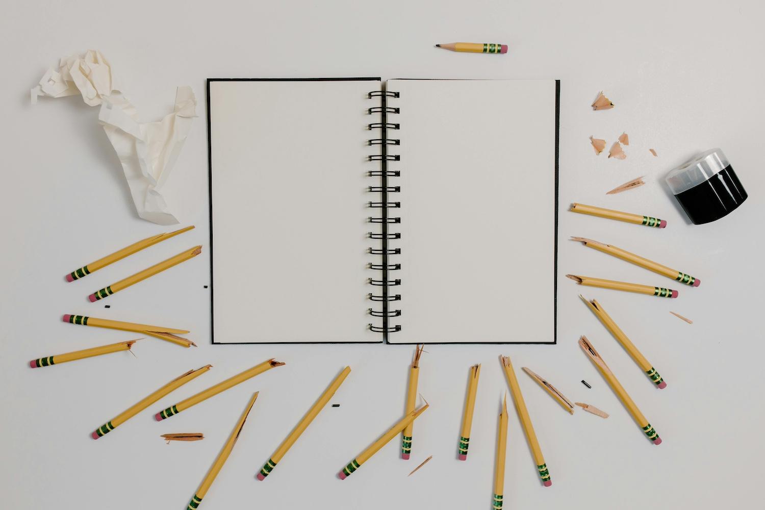 A notebook surrounded by broken pencils — failure. 
