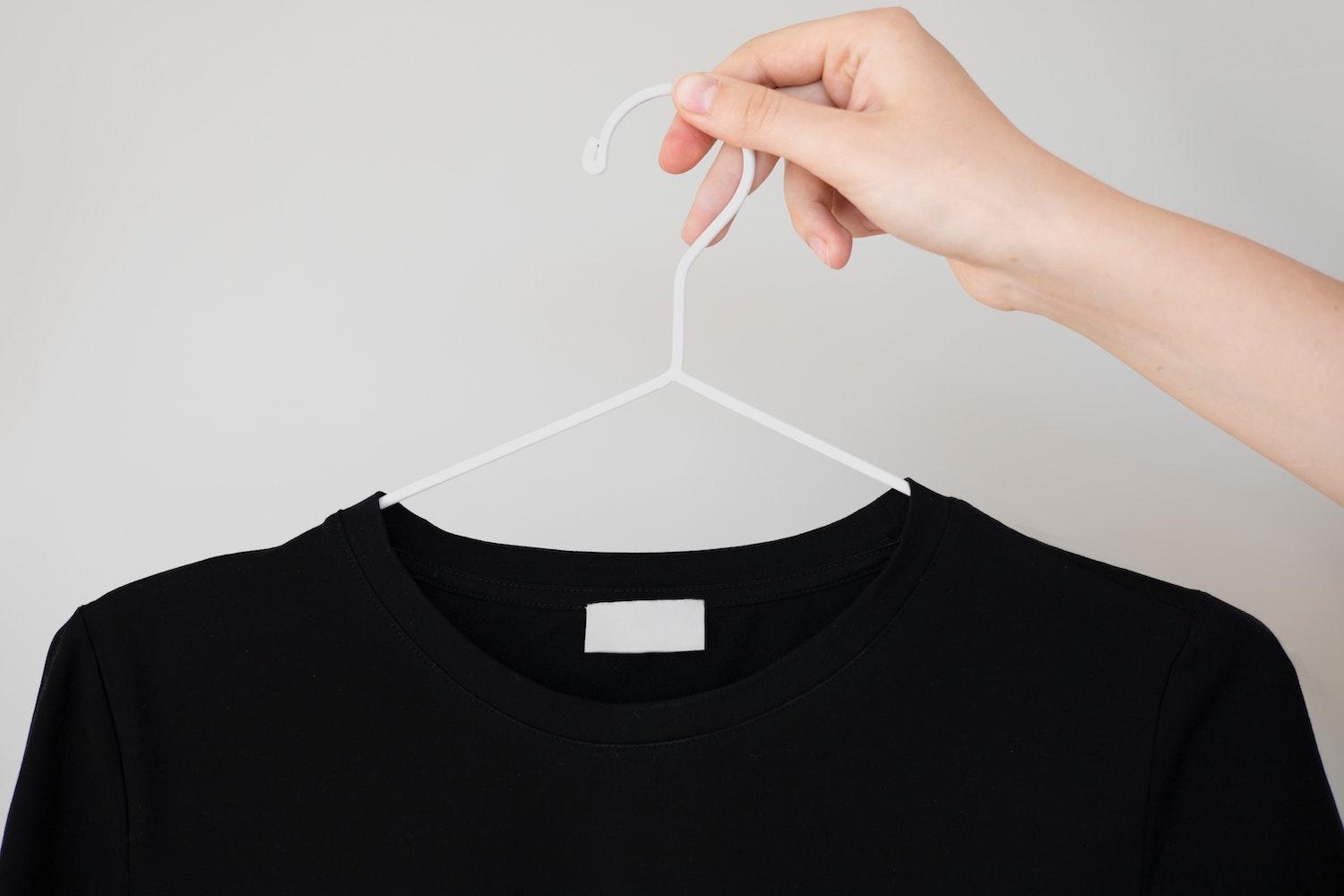 A black shirt on a hanger with a blank care label. 