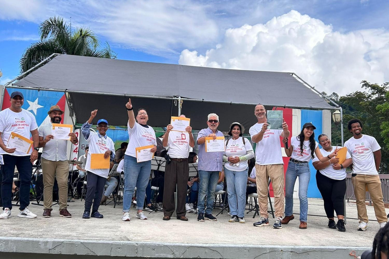 The Interstate Renewable Energy Council Puerto Rico team and residents of Castañer stand together celebrating — grid resilience
