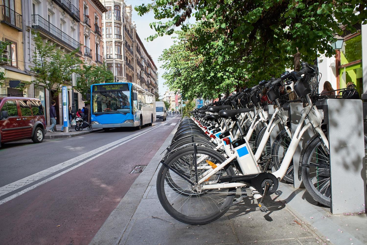 row of shared bike rentals with a bus in the background - public transportation