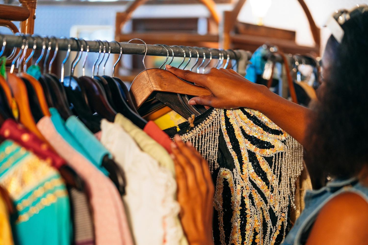 A person looking though a rack of secondhand clothing — tariffs