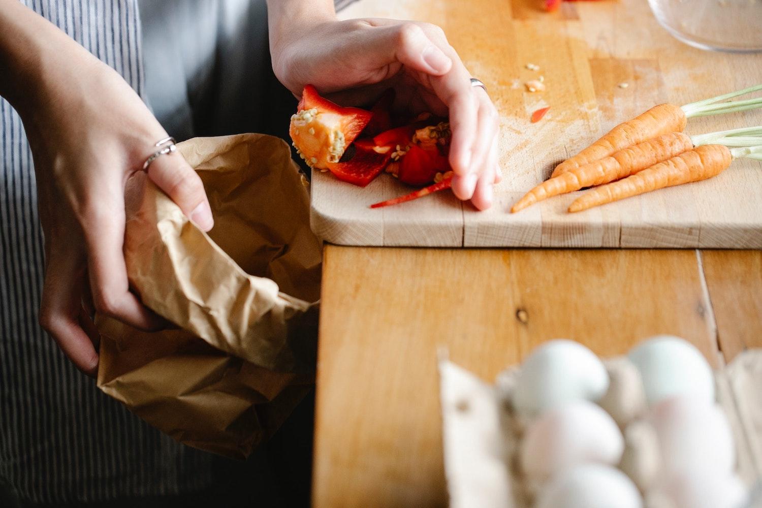 woman discarding vegetable scraps - composting as a solution to methane pollution