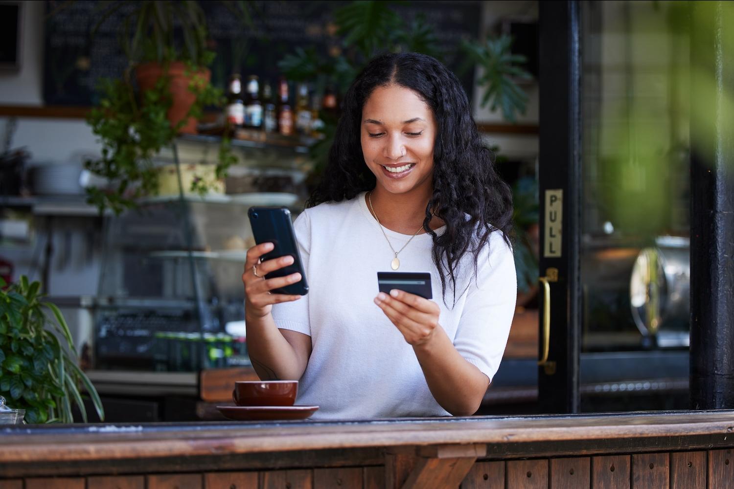 woman using a credit card and phone for online banking — financial equity — closing the racial wealth gap