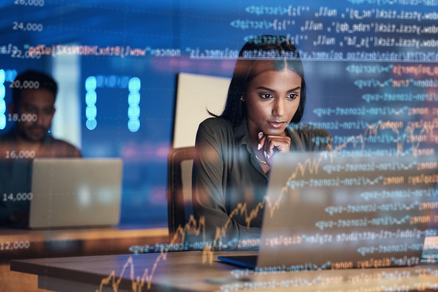 woman using the computer with hologram of code in front of her — women in tech