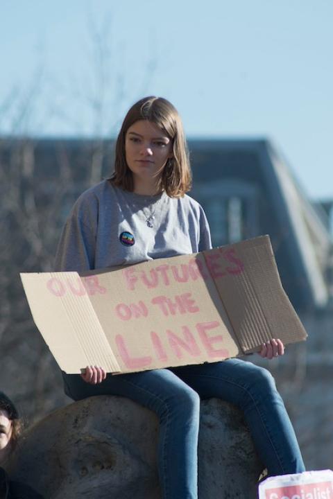 A protester with a sign that reads "Our future's on the line." — American Climate Corps
