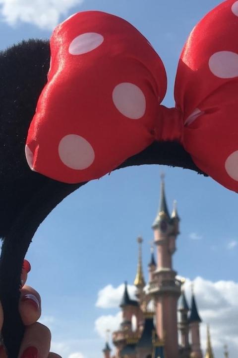 Disney World — woman holds Minnie Mouse headband over magic castle