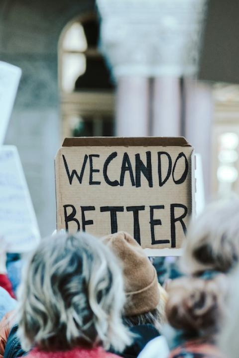 A protester holding a sign that reads "We can do better." 