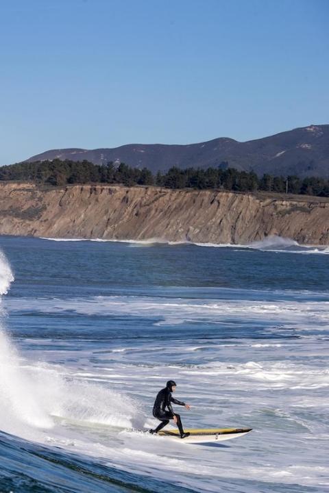 A person surfs in a Patagonia wetsuit at Half Moon Bay in California.