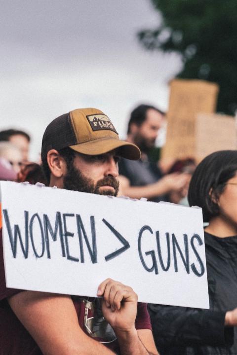 protester holds sign that reads women over guns - protesting gun violence and restrictive abortion policies