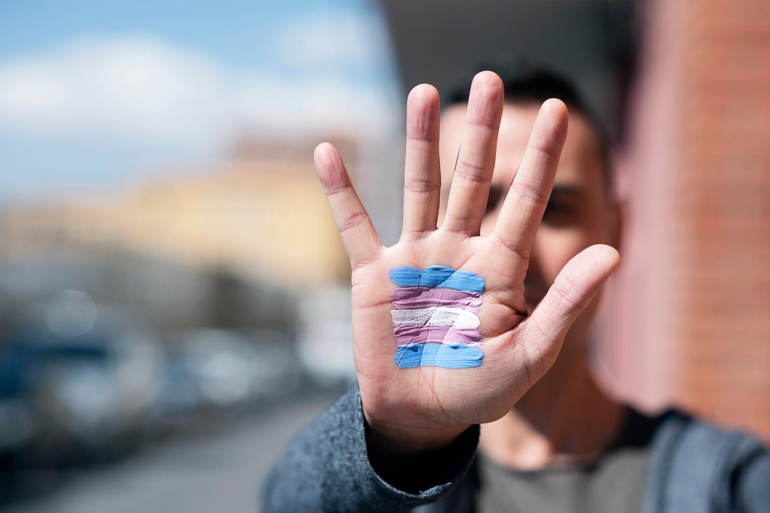 Man with transgender flag painted on the palm of his hand - transgender rights - transitioning