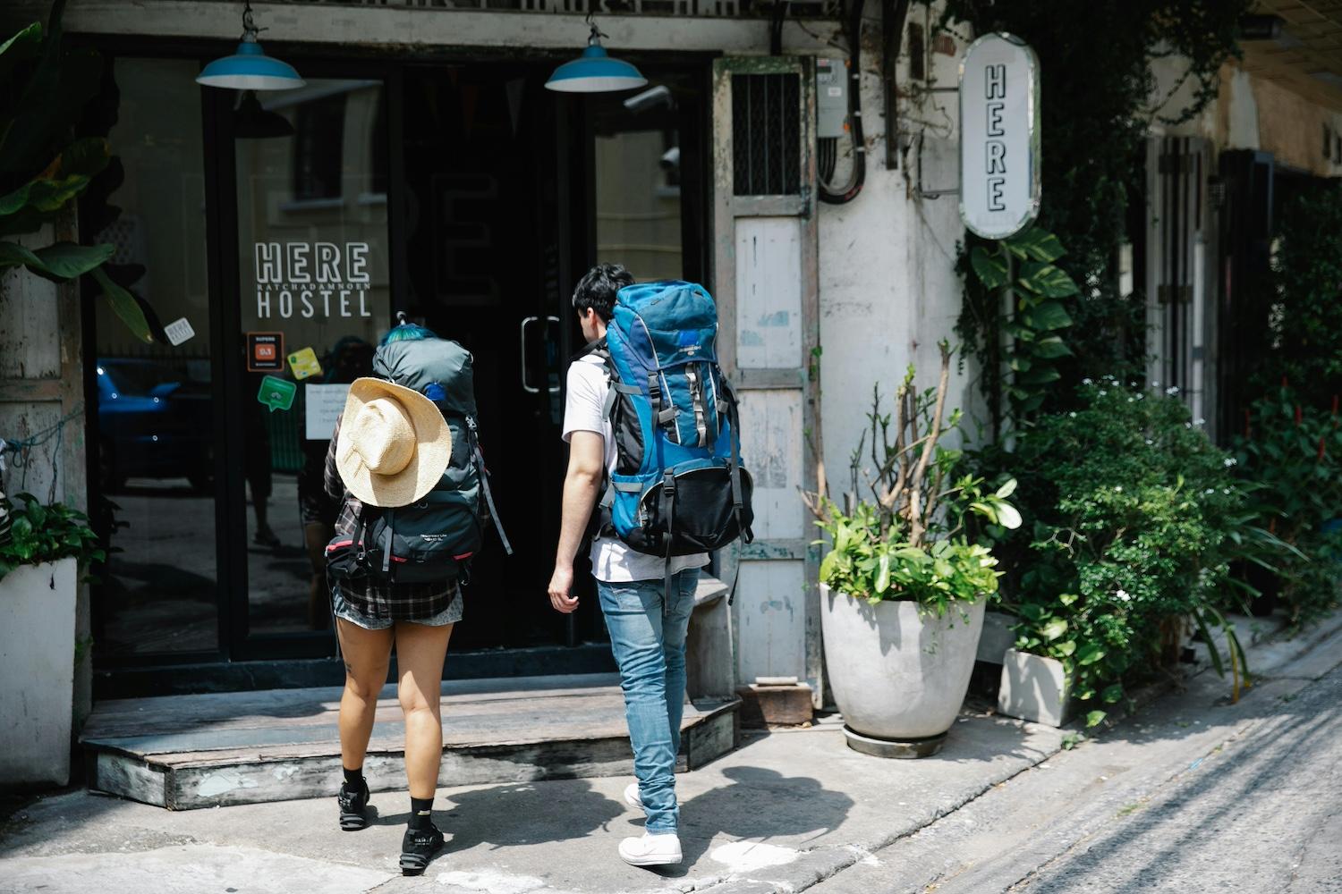 Two backpackers walking into a hostel. 
