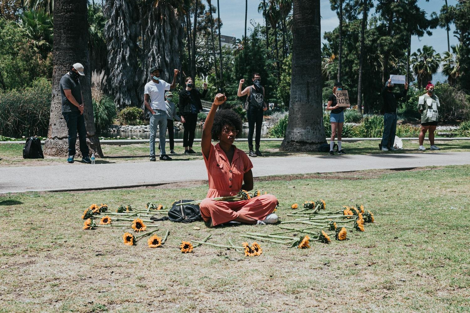 woman sitting in a circle of flowers at a social justice and civil rights demonstration in south carolina after the murder of george floyd